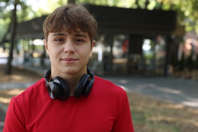 Photo of Portrait of teenage boy with headphones in park, space for text