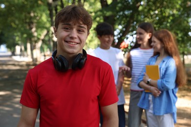 Photo of Portrait of teenage boy with headphones in park, selective focus