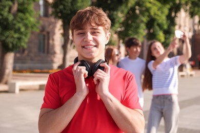 Photo of Portrait of teenage boy with headphones on city street, selective focus