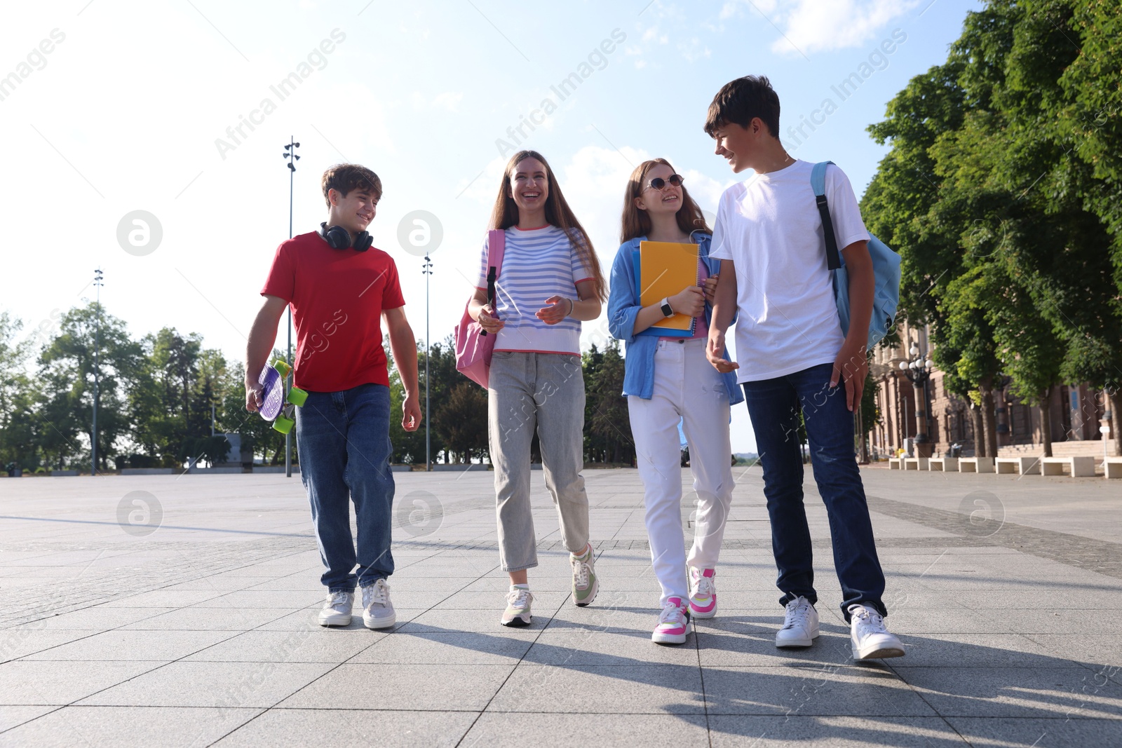Group of teenagers walking together on city street Photo of Group of teenagers walking together on city street