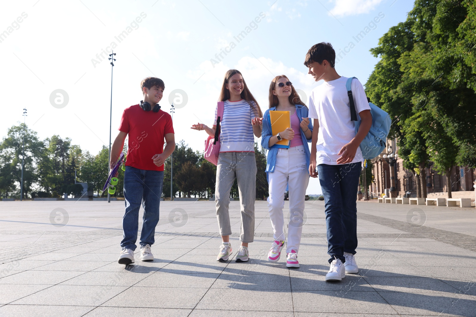 Group of teenagers walking together on city street Photo of Group of teenagers walking together on city street