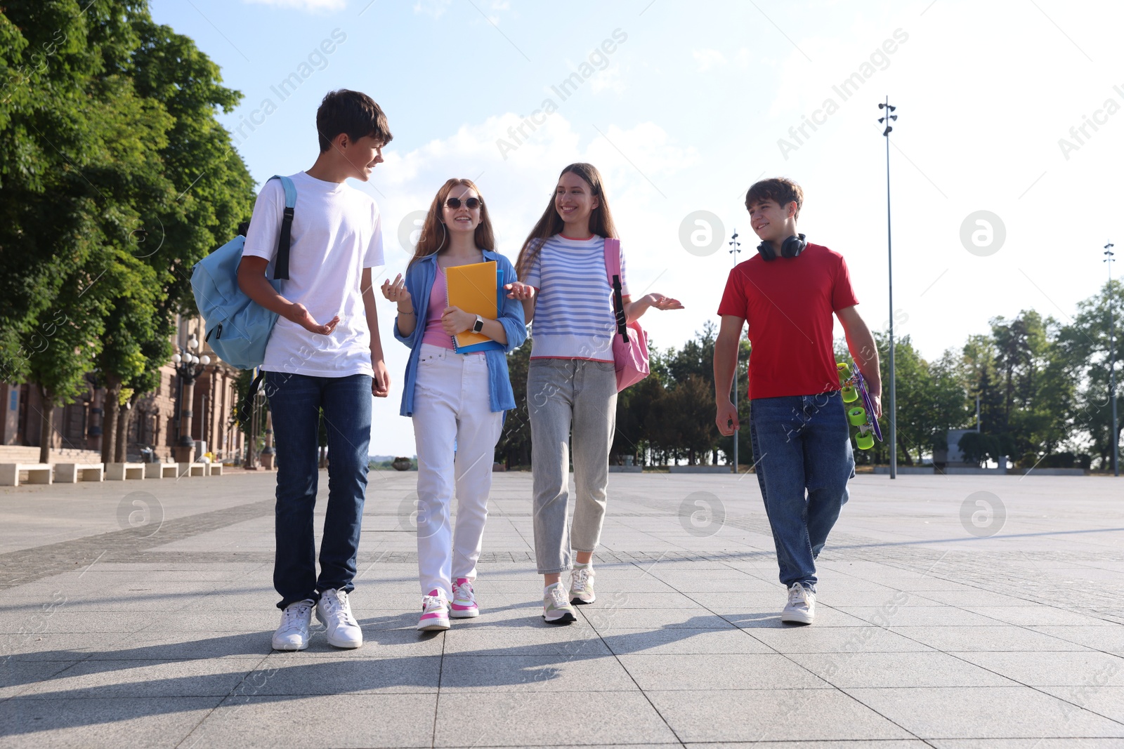 Group of teenagers walking together on city street Photo of Group of teenagers walking together on city street