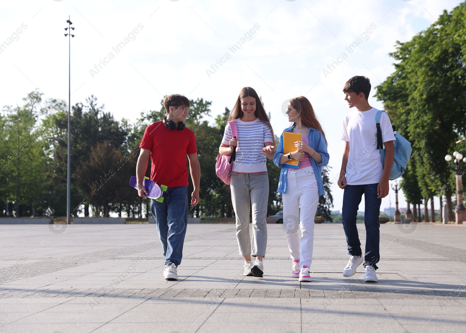 Group of teenagers walking together on city street Photo of Group of teenagers walking together on city street