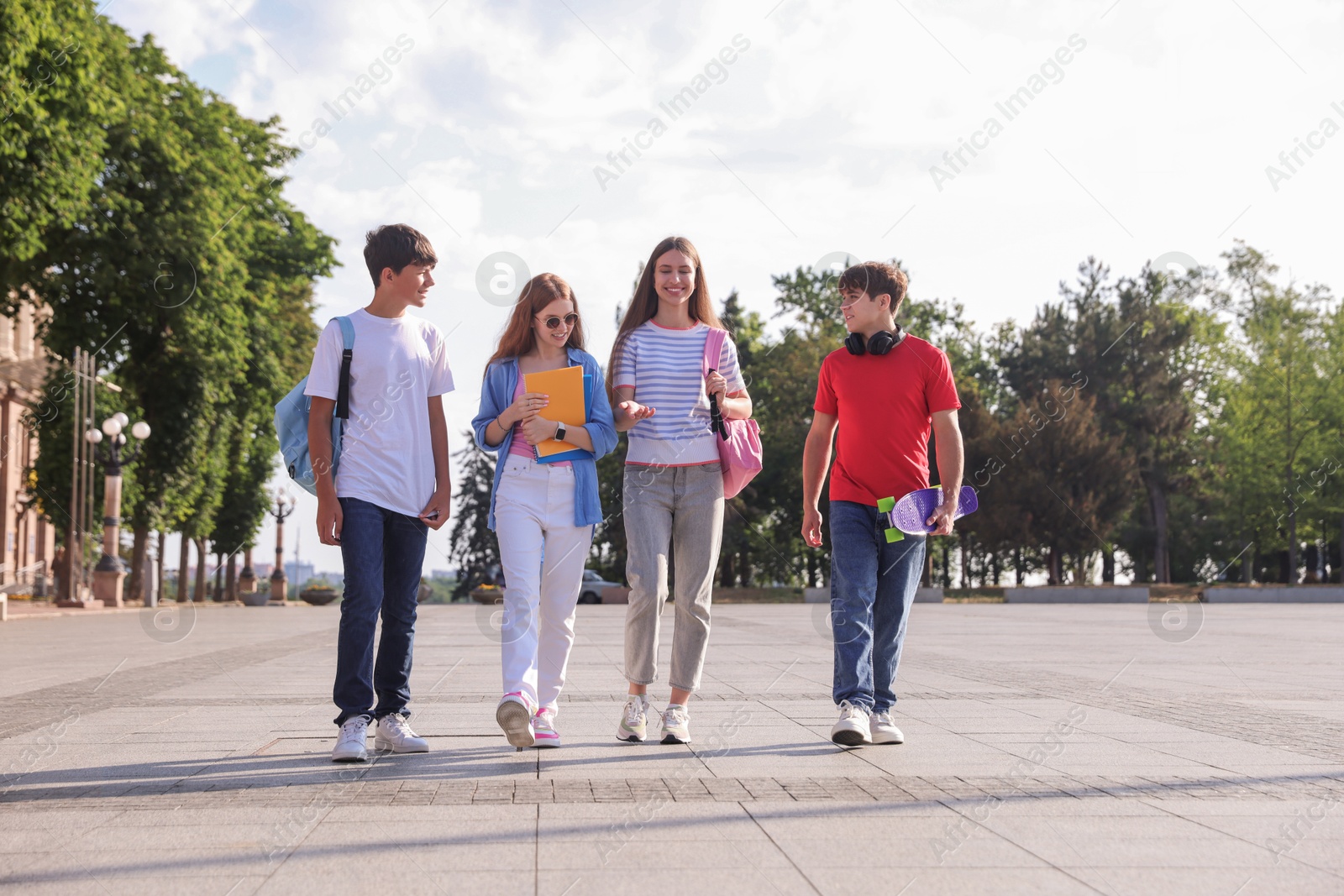 Group of teenagers walking together on city street Photo of Group of teenagers walking together on city street