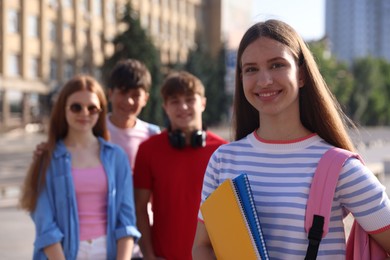 Photo of Group of teenagers walking together on city street, selective focus