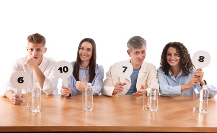 Photo of Panel of judges voting with score signs at table on white background