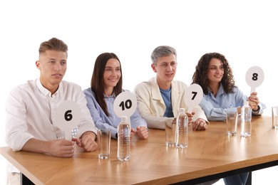 Photo of Panel of judges voting with score signs at table on white background