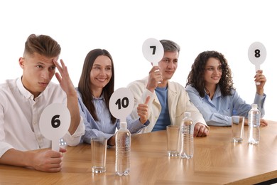 Photo of Panel of judges voting with score signs at table on white background