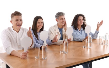 Photo of Panel of judges with blank score signs at table on white background