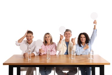 Photo of Panel of happy judges with blank score signs at table on white background