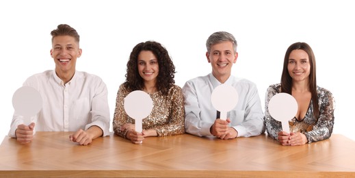 Photo of Panel of happy judges with blank score signs at table on white background