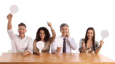 Photo of Panel of happy judges with blank score signs at table on white background