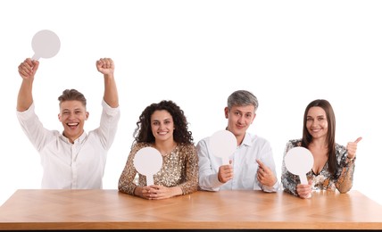 Photo of Panel of happy judges with blank score signs at table on white background