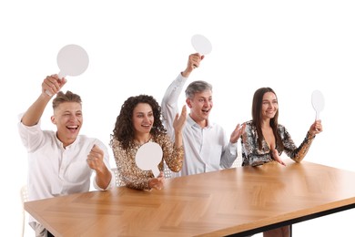 Photo of Panel of happy judges with blank score signs at table on white background
