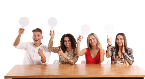 Photo of Panel of happy judges with blank score signs at table on white background
