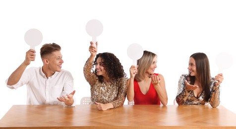 Photo of Panel of happy judges with blank score signs at table on white background