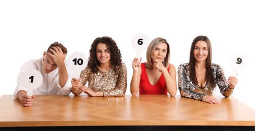 Photo of Panel of judges voting with score signs at table on white background