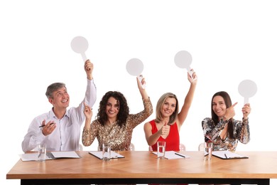 Photo of Panel of happy judges with blank score signs at table on white background