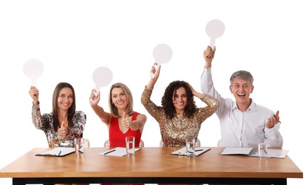 Photo of Panel of happy judges with blank score signs at table on white background