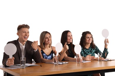 Photo of Panel of happy judges with blank score signs at table on white background
