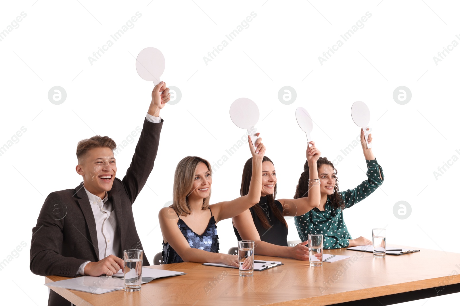 Panel of happy judges with blank score signs at table on white background Photo of Panel of happy judges with blank score signs at table on white background