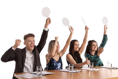 Photo of Panel of happy judges with blank score signs at table on white background