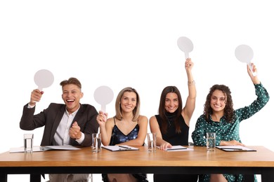 Photo of Panel of happy judges with blank score signs at table on white background