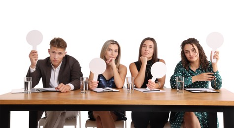 Photo of Panel of judges with blank score signs at table on white background