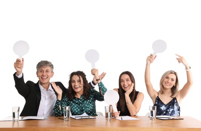 Photo of Panel of happy judges with blank score signs at table on white background