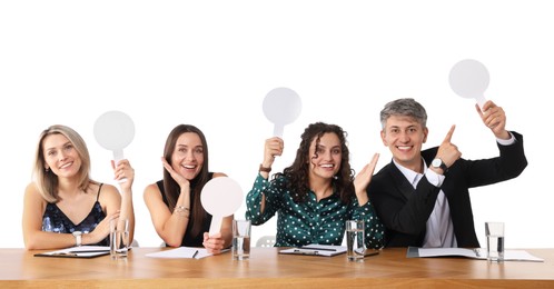 Photo of Panel of happy judges with blank score signs at table on white background