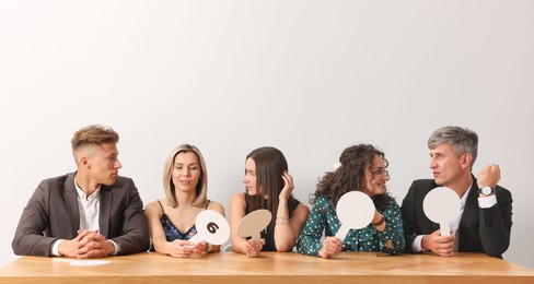 Photo of Panel of judges consulting at table against light grey background
