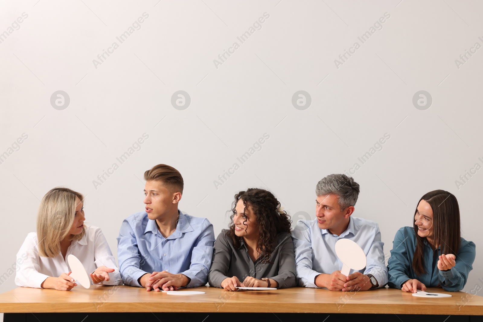 Panel of judges consulting at table against light grey background Photo of Panel of judges consulting at table against light grey background