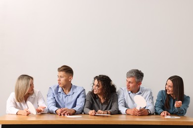 Photo of Panel of judges consulting at table against light grey background