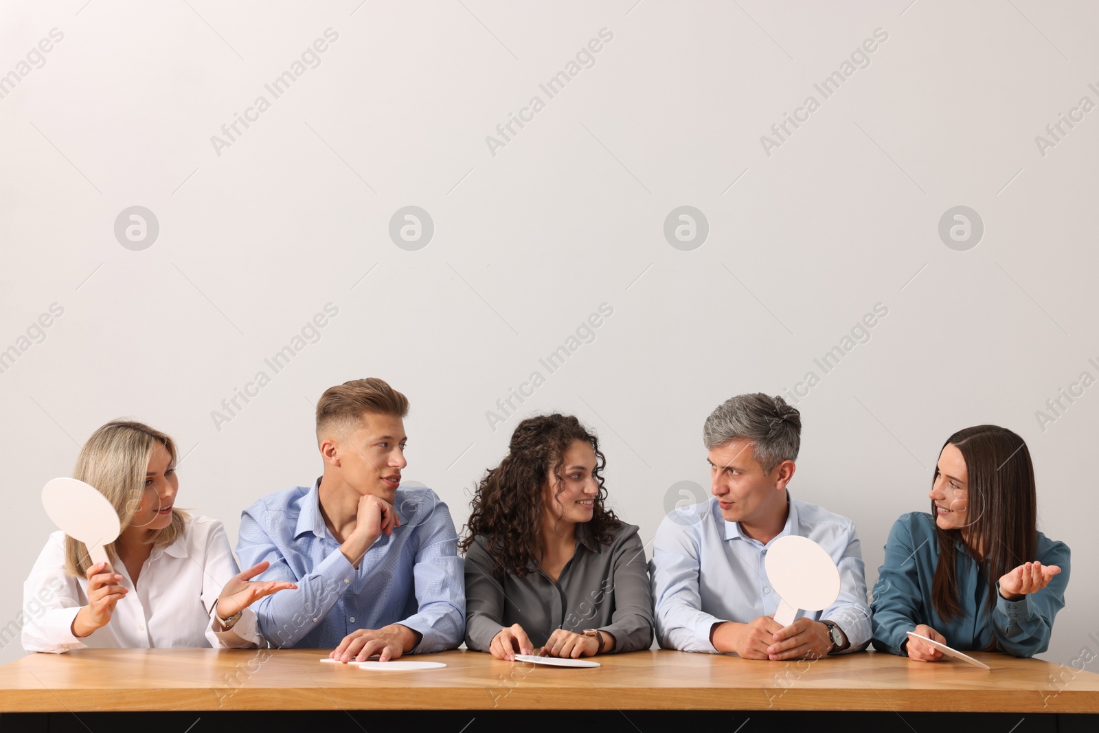 Panel of judges consulting at table against light grey background Photo of Panel of judges consulting at table against light grey background