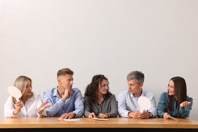 Photo of Panel of judges consulting at table against light grey background