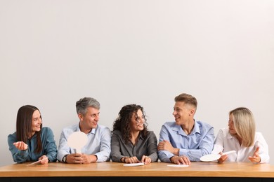 Photo of Panel of judges consulting at table against light grey background