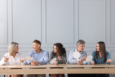 Photo of Panel of judges consulting at tables near grey wall