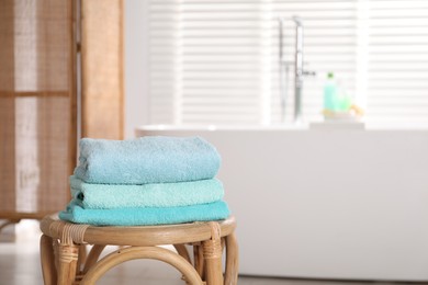 Photo of Stack of colorful towels on table in bathroom, space for text