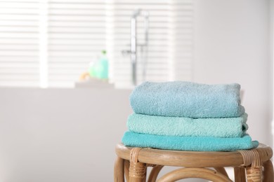 Photo of Stack of colorful towels on table in bathroom, space for text