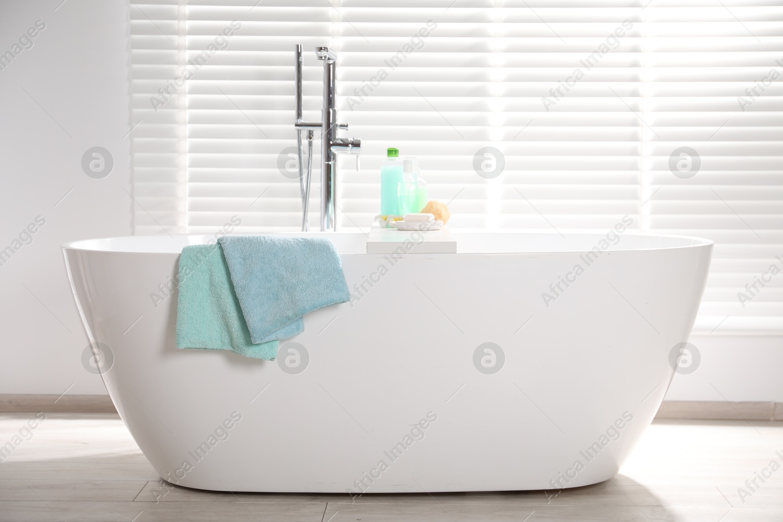Soft towels on tub near window in bathroom Photo of Soft towels on tub near window in bathroom
