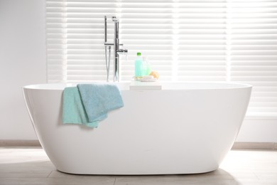 Photo of Soft towels on tub near window in bathroom