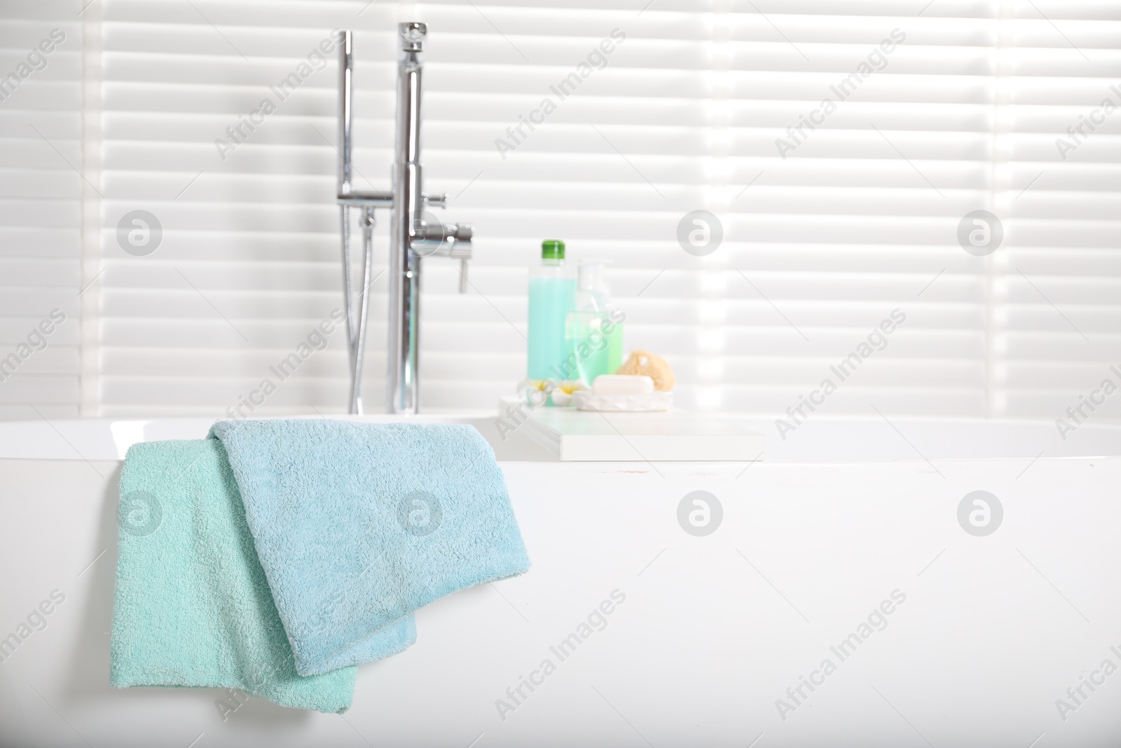 Soft towels on tub near window in bathroom Photo of Soft towels on tub near window in bathroom