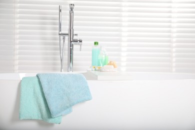 Photo of Soft towels on tub near window in bathroom