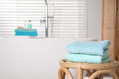 Photo of Stack of colorful towels on table near tub in bathroom, space for text