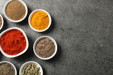 Photo of Different aromatic spices on grey table, flat lay. Space for text