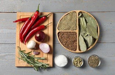 Photo of Different aromatic spices on grey wooden table, flat lay