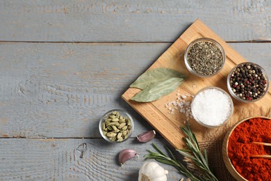 Photo of Different aromatic spices on grey wooden table, flat lay. Space for text