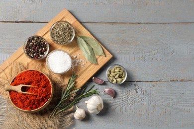 Photo of Different aromatic spices on grey wooden table, flat lay. Space for text
