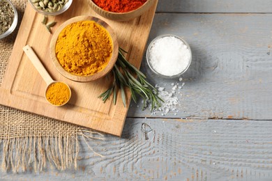 Photo of Different aromatic spices on grey wooden table, flat lay. Space for text