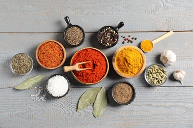 Photo of Different aromatic spices on grey wooden table, flat lay
